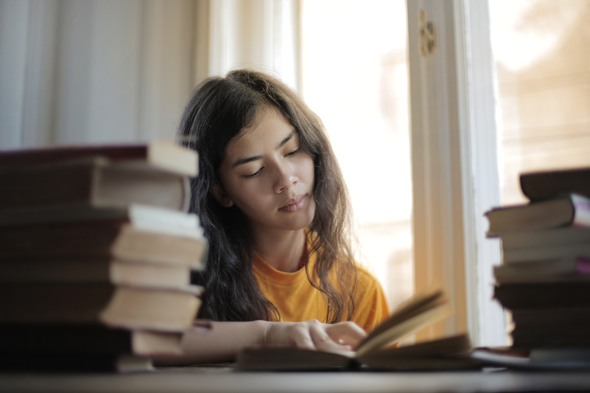 Clever lady with curly hair reading book